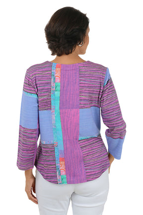 Woman wearing a colorful patterned top with white pants on a white background