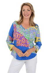 Woman wearing a colorful patterned top on a white background.
