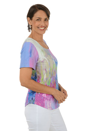 Woman wearing a colorful abstract patterned top on a white background. Side shot.