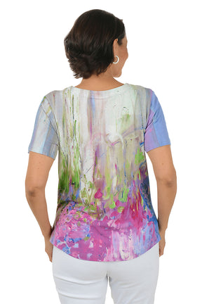 Woman wearing a colorful abstract patterned top on a white background. Back shot.