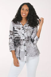 Woman wearing a patterned shirt and white pants on a white background