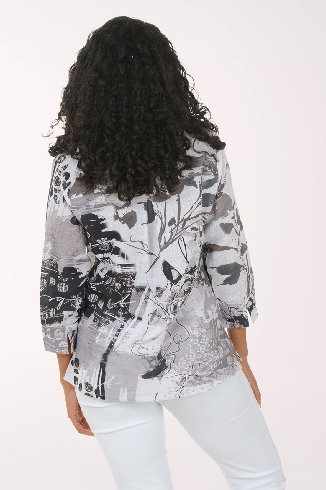 Woman wearing a patterned shirt and white pants on a white background