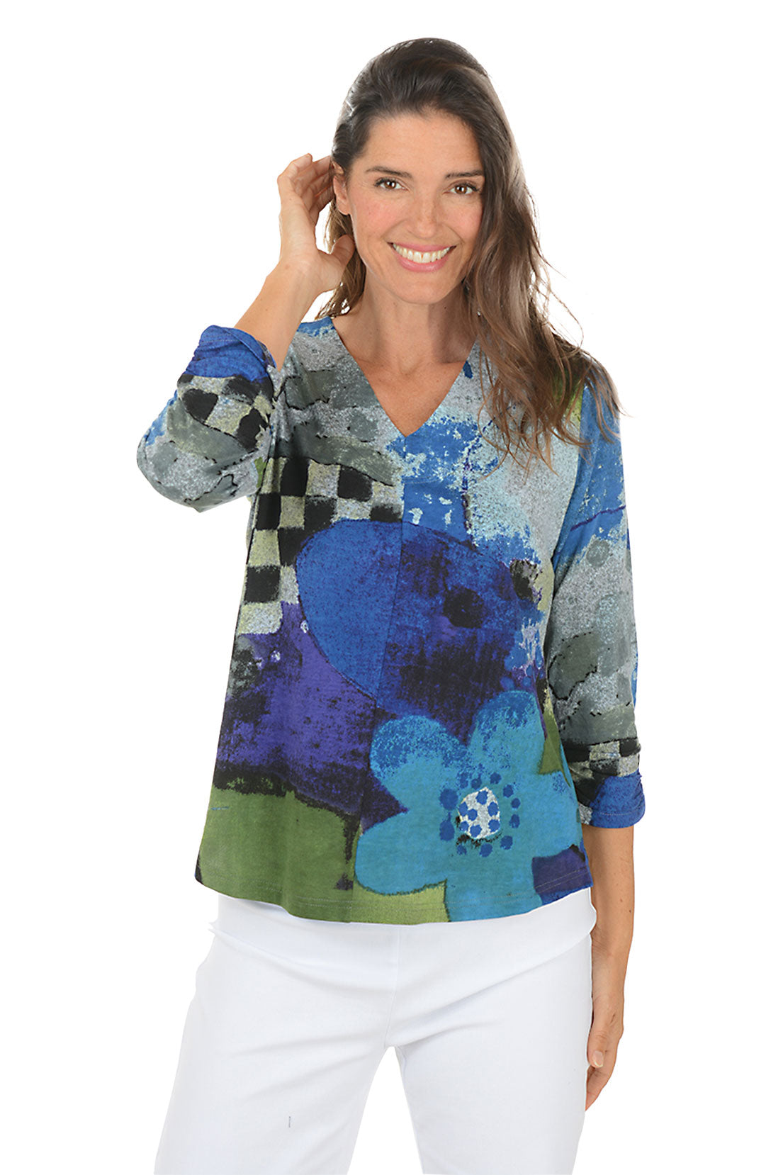 Woman wearing a blue multi colorful floral blouse with white pants on a white background.