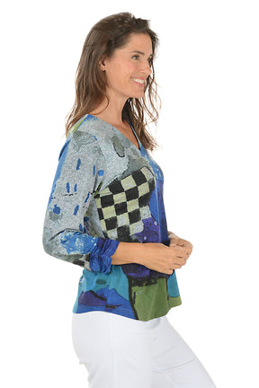 Woman wearing a blue multi colorful floral blouse with white pants on a white background. Side shot.