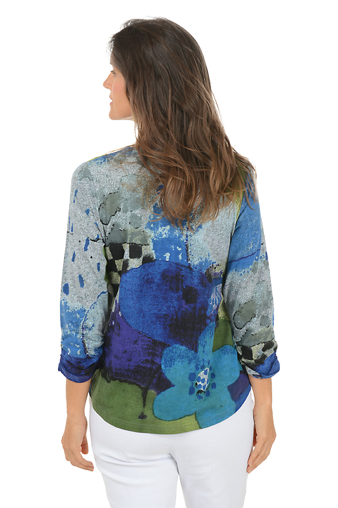 Woman wearing a blue multi colorful floral blouse with white pants on a white background. Back shot.