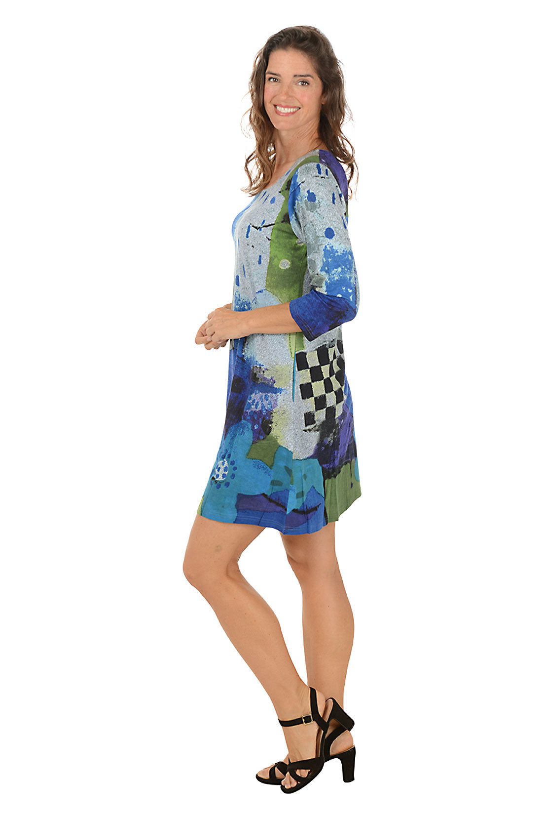 Woman wearing a colorful dress with abstract patterns on a white background. Side shot.