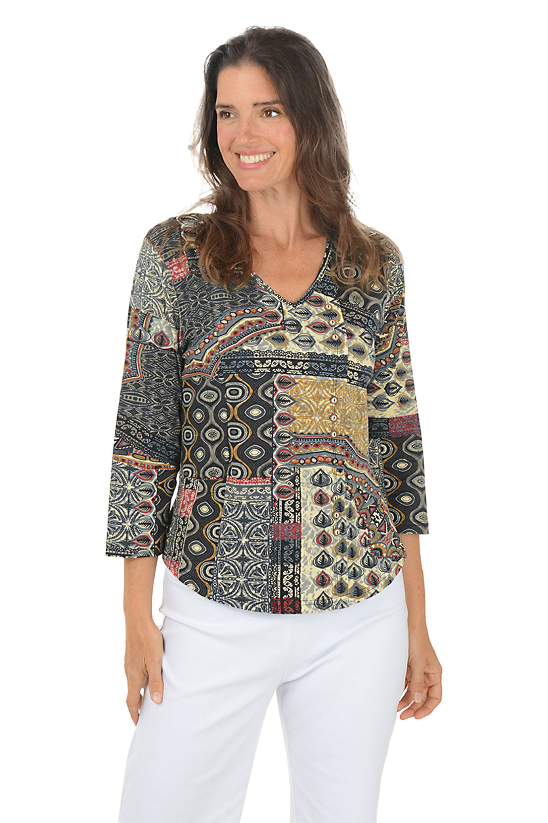 Woman wearing a 3/4 sleeve paisley patterned blouse and white pants on a white background.