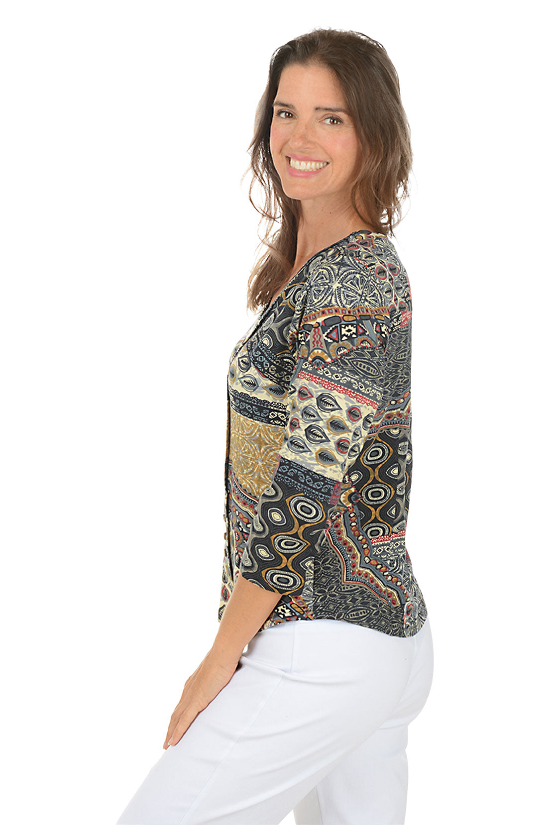 Woman wearing a 3/4 sleeve paisley patterned blouse and white pants on a white background. Side shot.