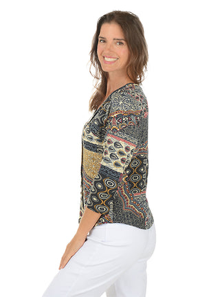 Woman wearing a 3/4 sleeve paisley patterned blouse and white pants on a white background. Side shot.