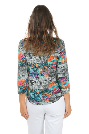 Woman wearing a colorful abstract patterned blouse with white pants on a white background. Back shot.