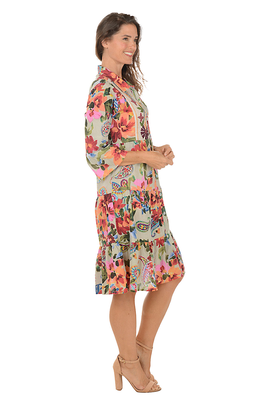Woman wearing a 3/4 sleeve collared floral dress on a white background. Side shot.
