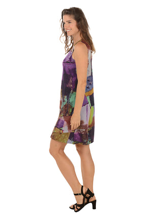 Woman wearing a sleeveless purple multi colorful dress on a white background. Side shot.