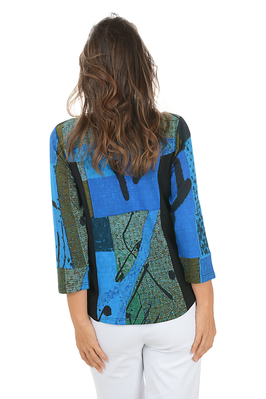 Woman wearing a colorful patterned top with white pants on a white background. Back shot.