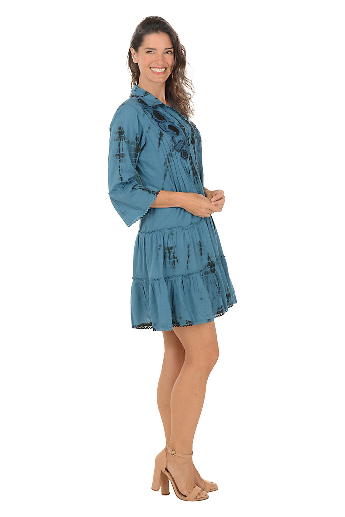 Woman wearing a blue dress with floral patterns on a white background. Side shot.