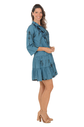 Woman wearing a blue dress with floral patterns on a white background. Side shot.