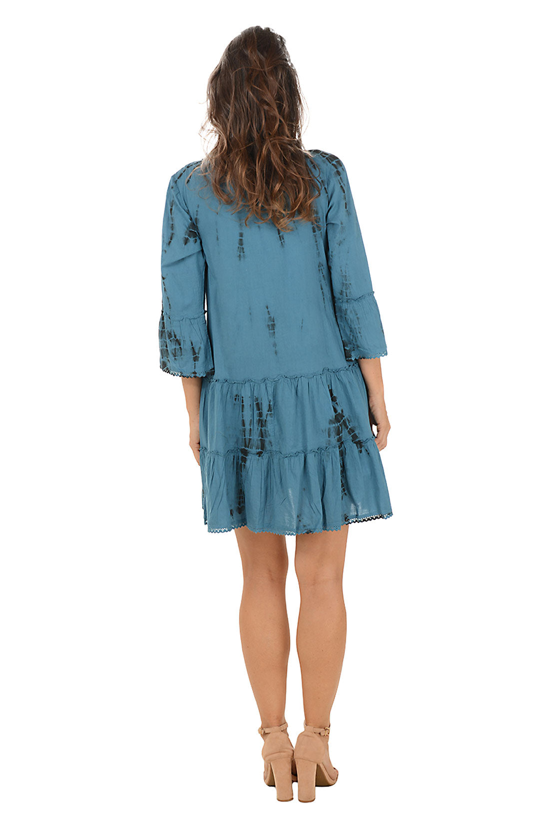 Woman wearing a blue dress with floral patterns on a white background. Back shot.