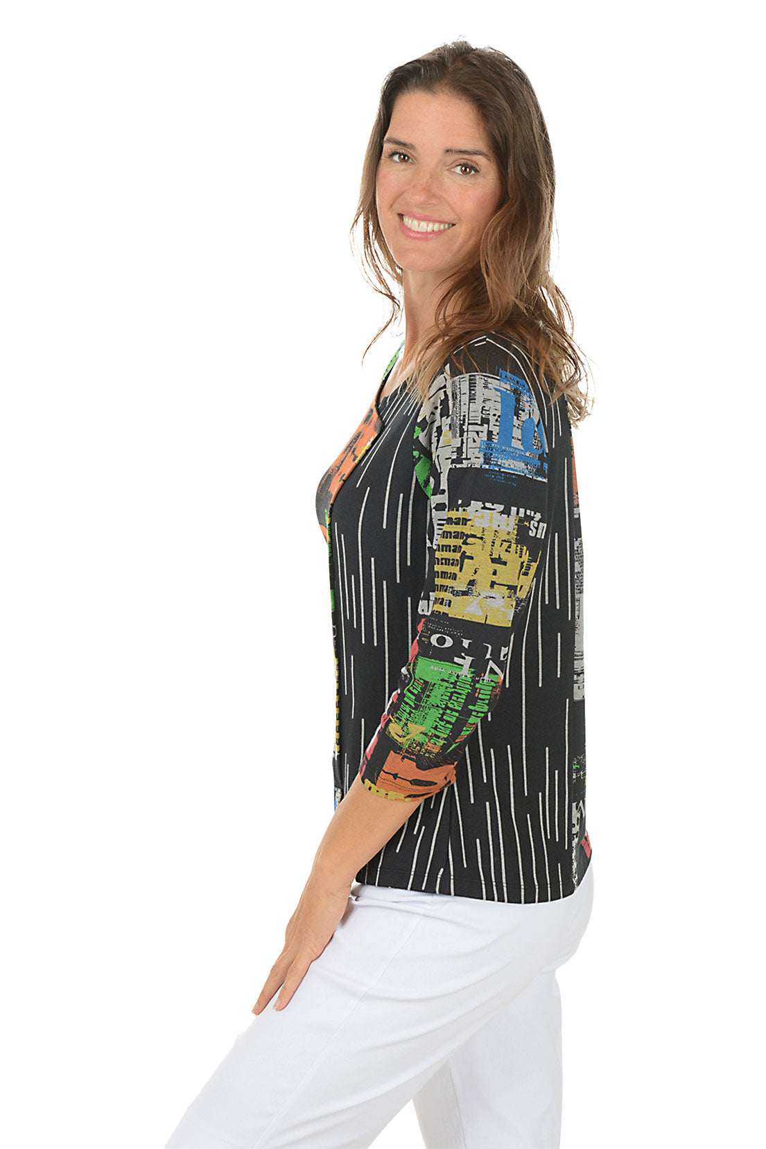 Woman wearing a 3/4 sleeve colorful typesetting patterned top with a white background. Side shot.