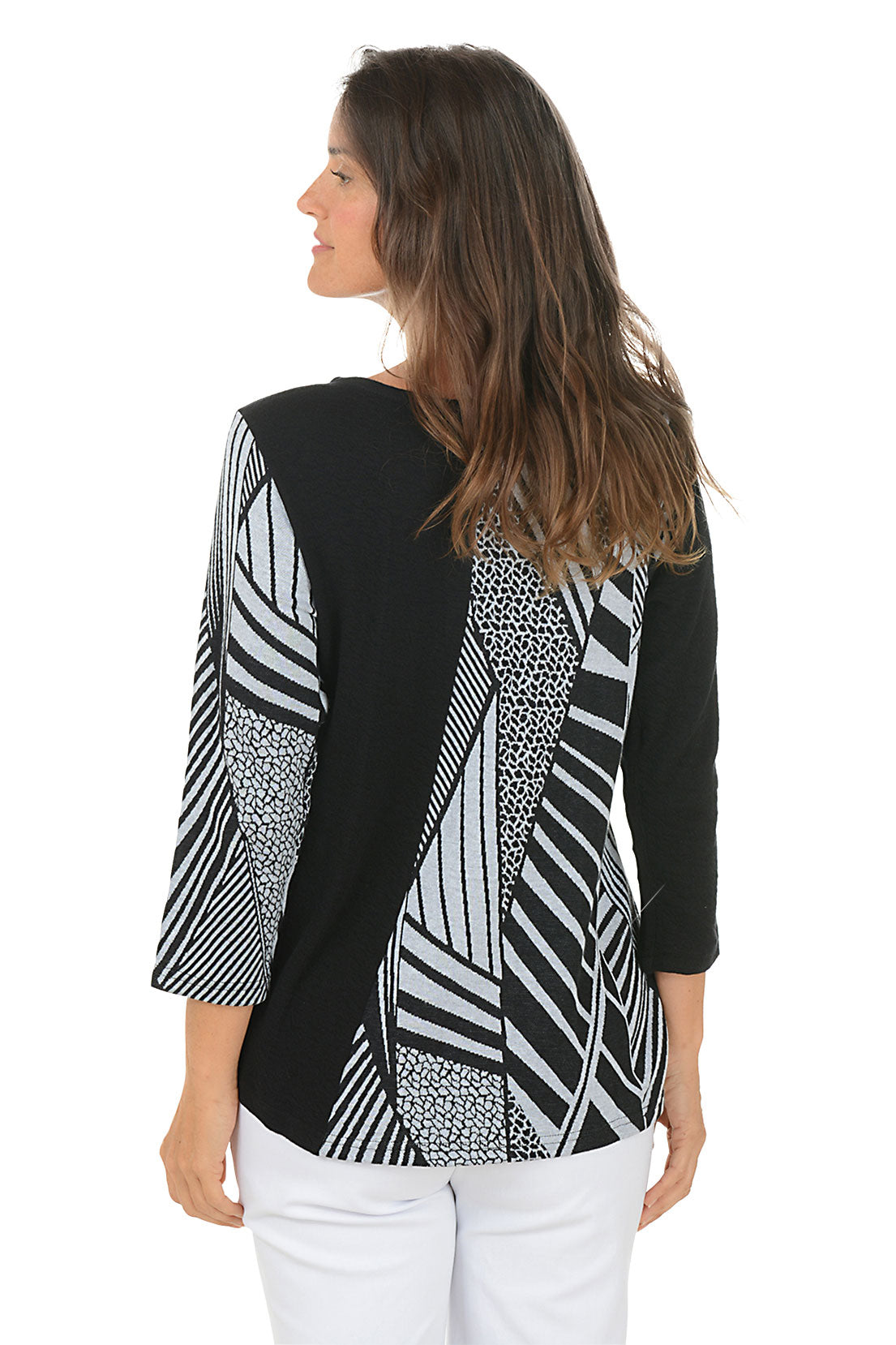 Woman wearing a black and white patterned blouse with a white background. Back shot.