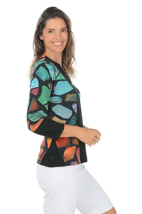Woman wearing a 3/4 sleeve patchwork patterned top with a contrasting cuff on a white background. Side shot.