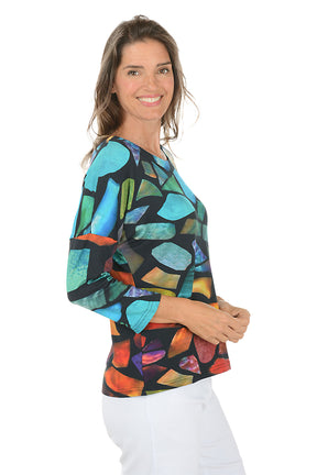 Woman wearing a 3/4 sleeve colorful abstract patterned top on a white background. Side shot.