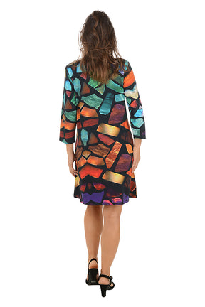 Woman wearing a 3/4 sleeve colorful abstract patterned dress with pockets on a white background. Back shot.