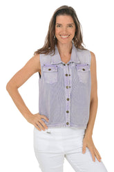 A woman wearing a purple button-front denim sweater vest with a fold-over collar, dual front pockets, and a straight hemline. She is also wearing white pants.