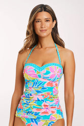 Front view of a woman wearing the Barcelona Bloom Sweetheart Neck Tankini Top, a turquoise tropical floral print with coral, pink, lime green and blue flowers, with a ruched sweetheart bandeau neckline, turquoise geometric-print piping, a halter strap and ruched sides.
