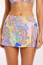 Close-up front view of the La Vida Bohemia High-Waisted Swim Skirt in a paisley patchwork print in pink, lavender, lime green, coral and cobalt blue, showing the high waist, short A-line shape and a side slit.