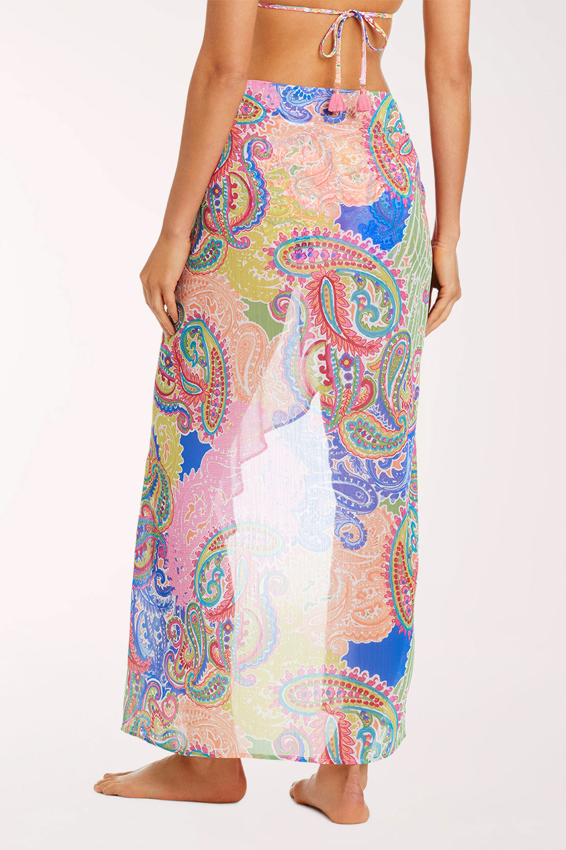 Back view of the La Vida Bohemia Ruffled Chiffon Sarong in a semi-sheer paisley patchwork print in pink, lavender, lime green, coral and cobalt blue, wrapped around the hips and falling to the ankles with a ruffled edge.