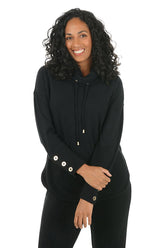 Woman wearing a black hoodie with button details on the arm on a white background.