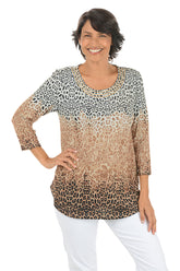 Woman wearing a tan 3/4 sleeve leopard print top and white pants on a white background.