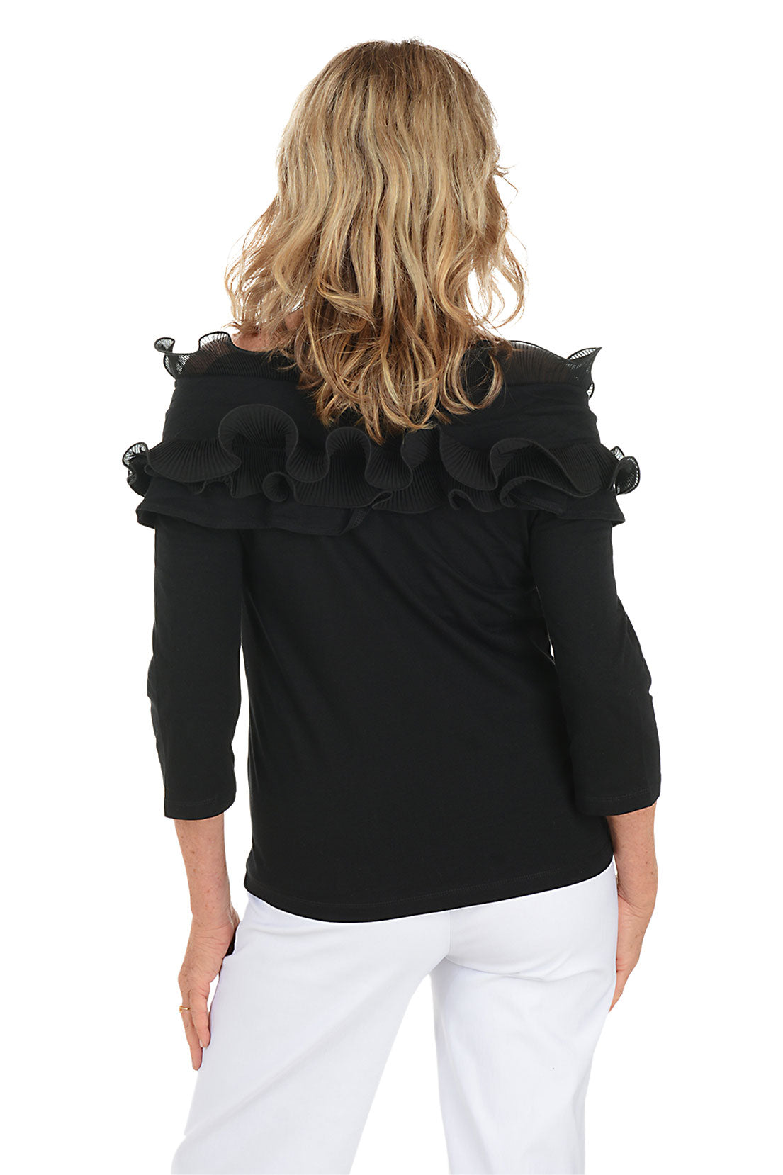 Woman wearing a black off-shoulder top with ruffles on a white background. Back shot.