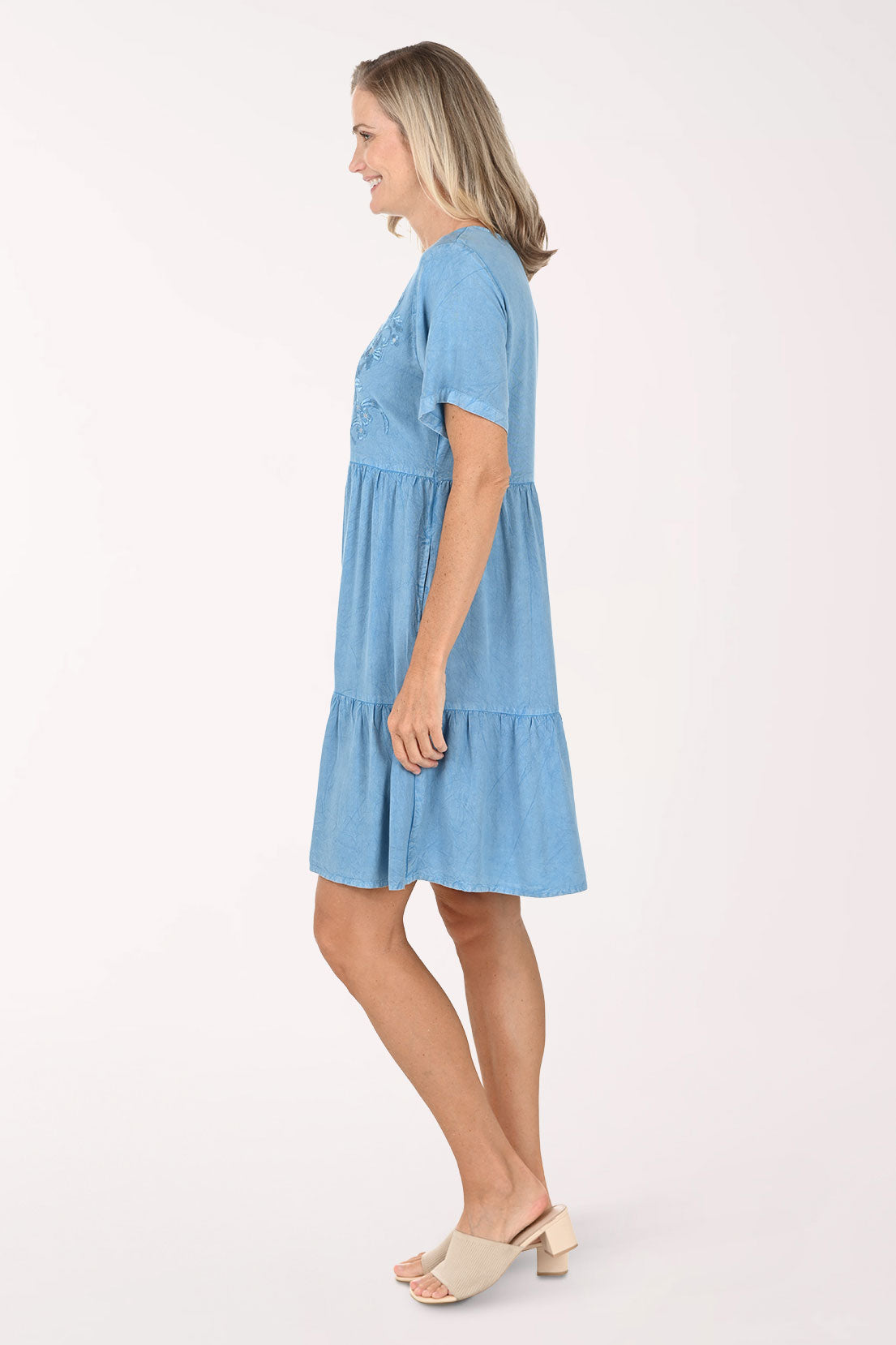 Woman wearing a blue dress with lace details on a white background