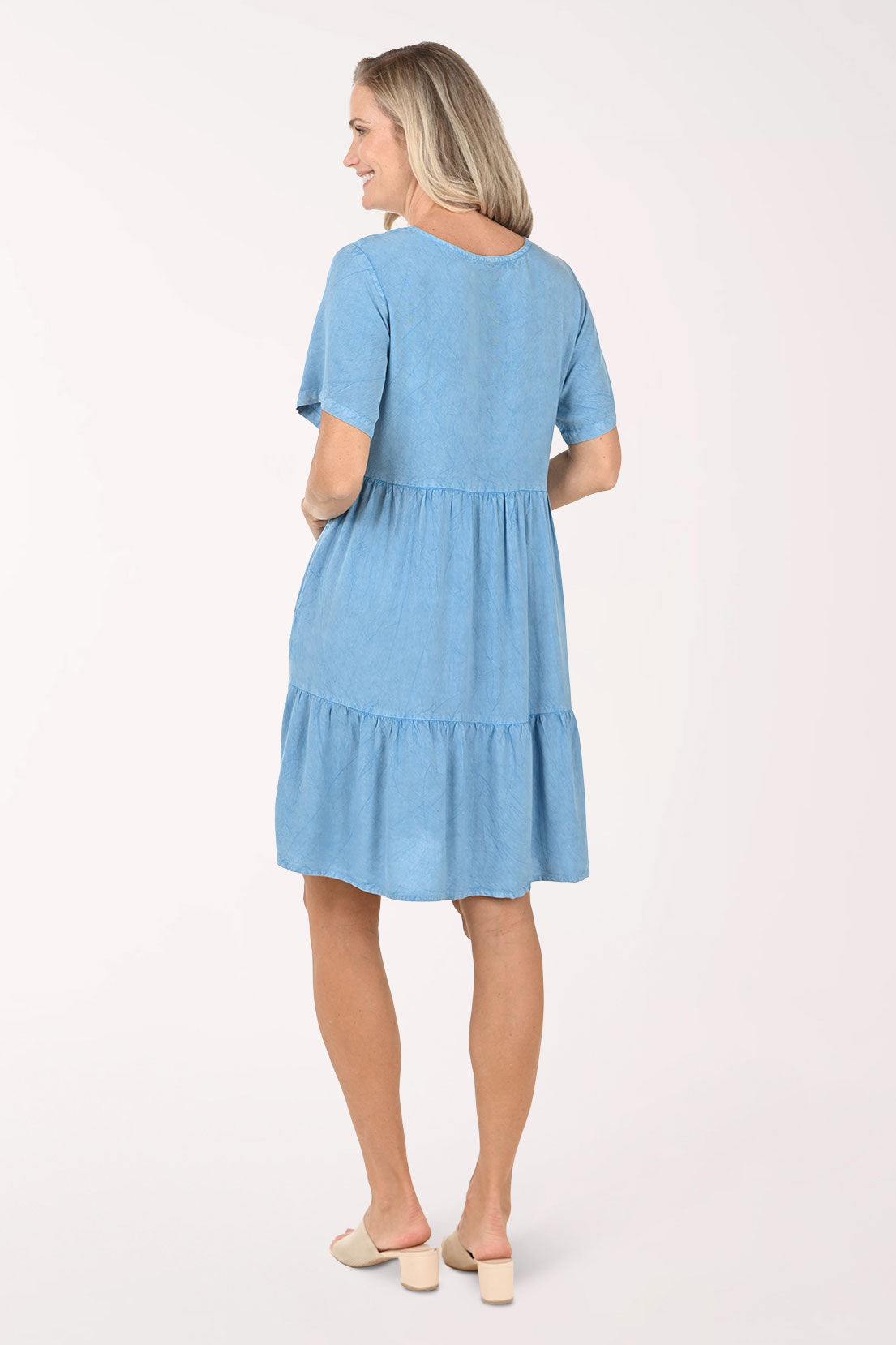 Woman wearing a blue dress with lace details on a white background