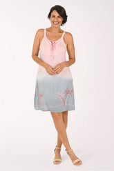 A woman modeling a sleeveless A-line dress with a pink and light blue ombre gradient, featuring a lace-up neckline and embroidered palm trees near the hem.