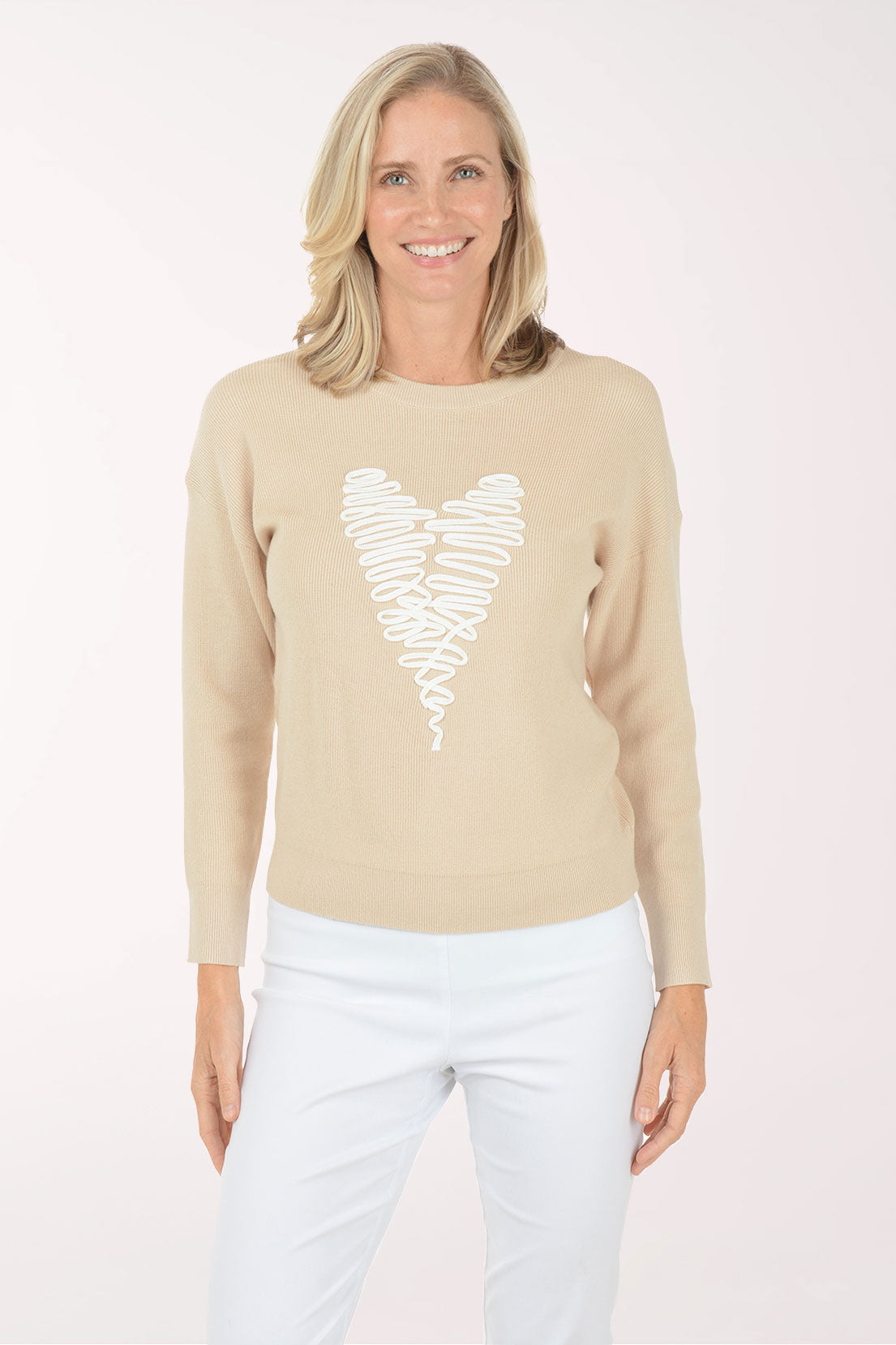 Woman wearing a beige sweater with a white heart design on a white background