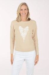 Woman wearing a beige sweater with a white heart design on a white background