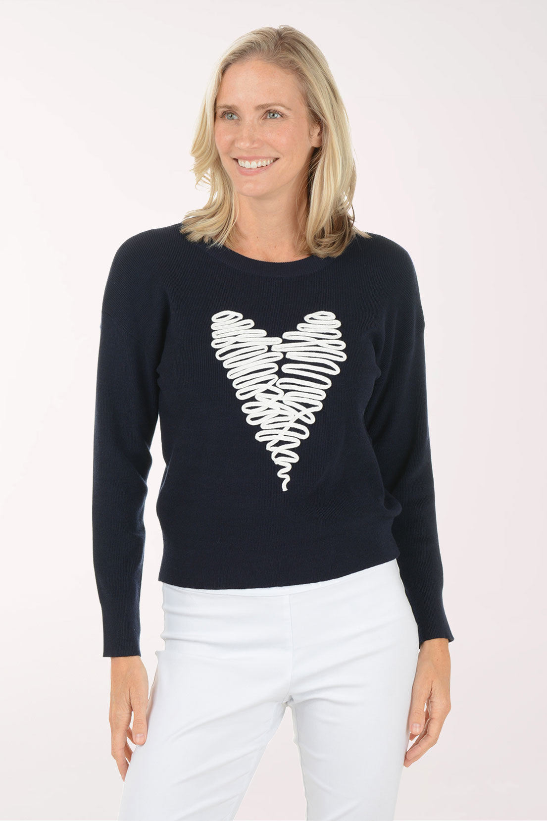 Woman wearing a navy sweater with a white heart design on a white background