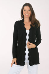 Woman wearing a black cardigan over a white top on a white background.
