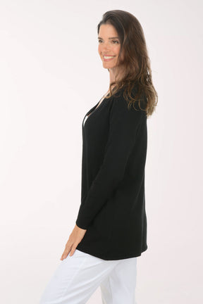 Woman wearing a black cardigan over a white top on a white background. Side shot.