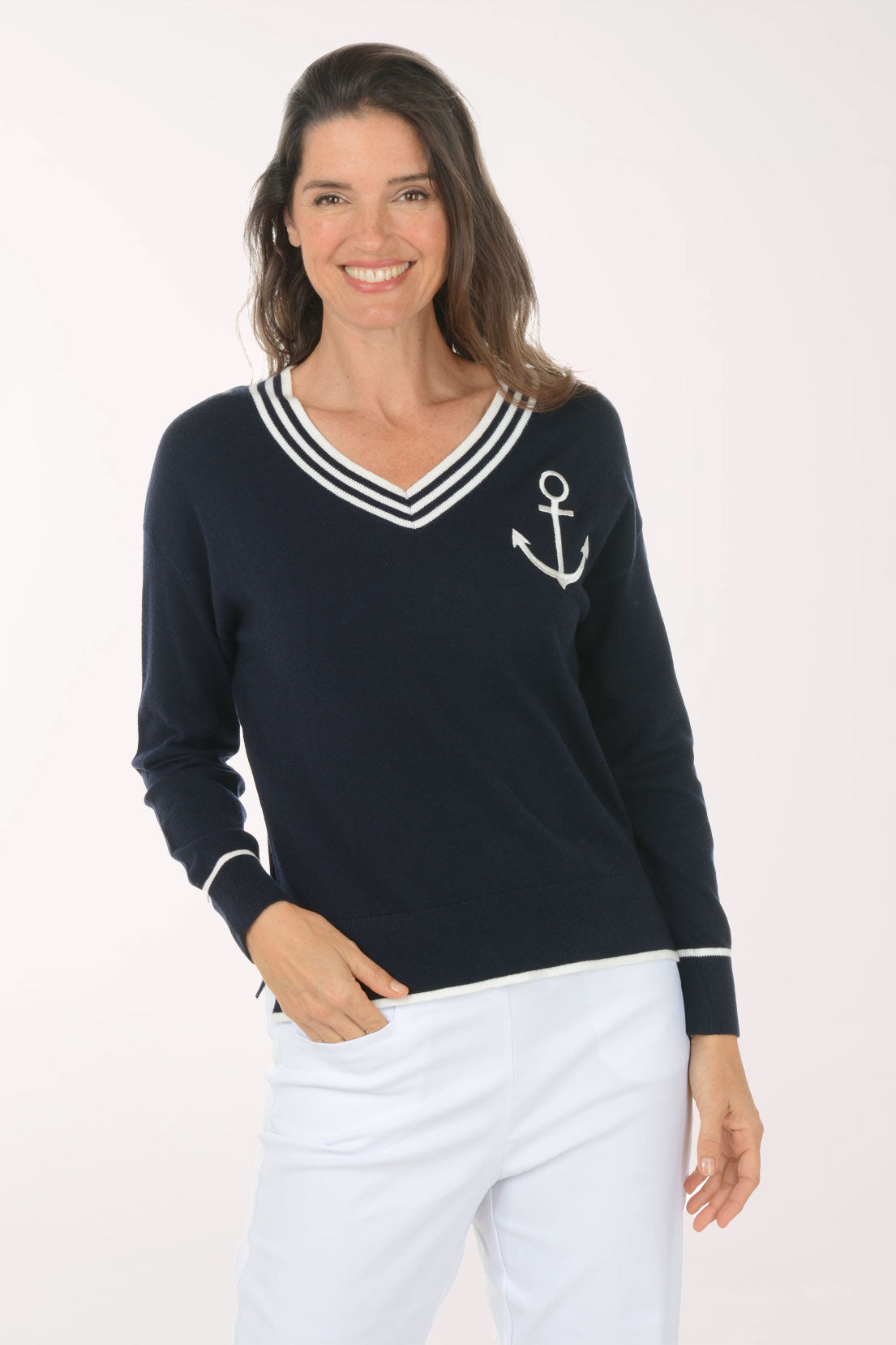 Woman wearing a navy sweater with an anchor design on a white background