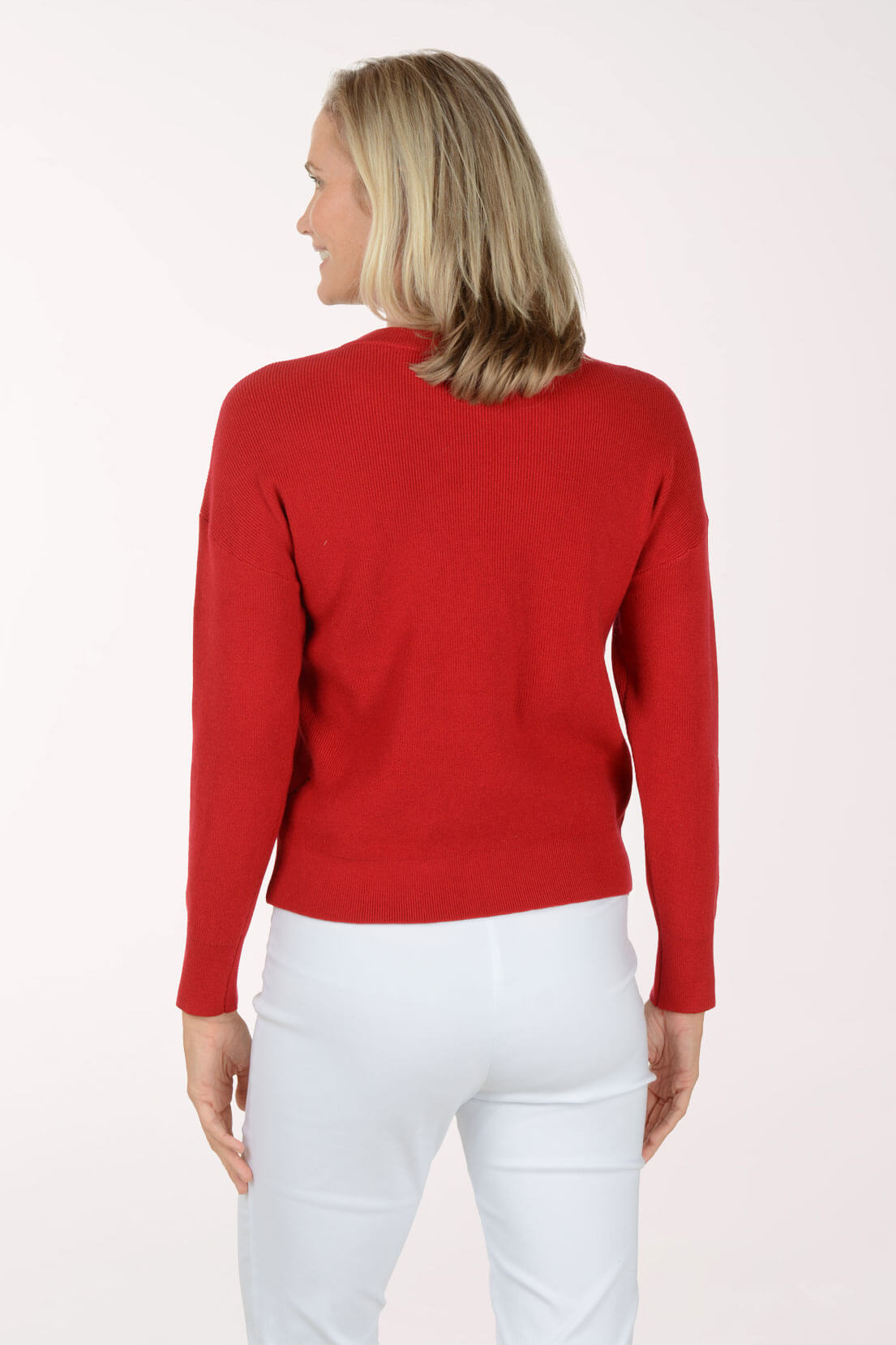 Woman wearing a red sweater and white pants on a white background. Back shot.