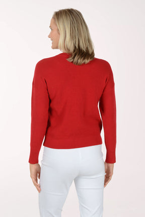 Woman wearing a red sweater and white pants on a white background. Back shot.