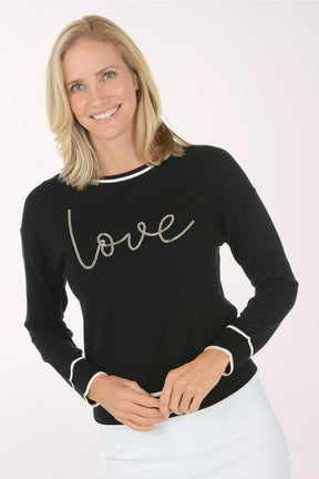 Woman wearing a black sweater with 'love' text on a white background