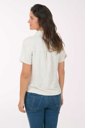 Woman wearing a beige patterned shirt and blue jeans on a white background