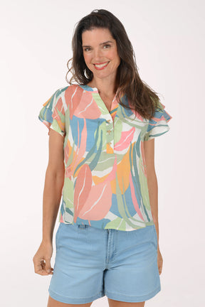 Woman wearing a colorful floral blouse and light blue shorts on a white background