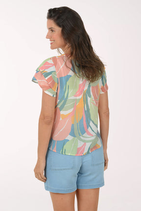 Woman wearing a colorful floral blouse and light blue shorts on a white background