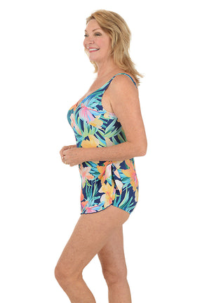 Woman wearing a colorful floral swimsuit on a white background. Side shot.