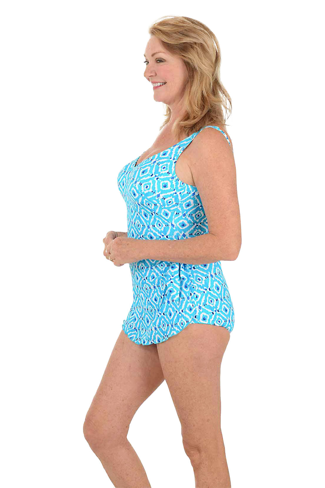 Woman wearing a blue patterned swimsuit on a white background. Side shot.