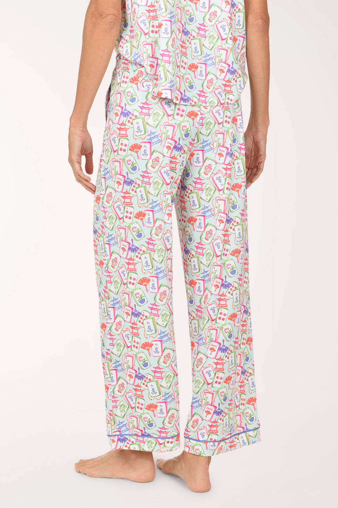 A person wearing a matching pajama set with a colorful all-over novelty print, shown from the waist down against a plain light background.